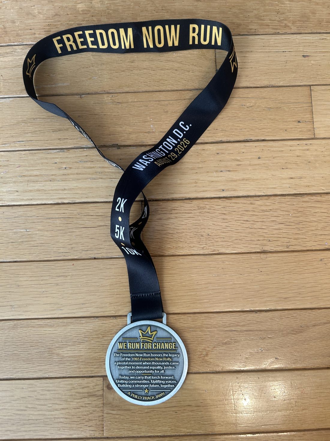 Back of the 2026 Freedom Now Run finisher medal, engraved with the words We Run For Change and a paragraph about honoring the legacy of the Freedom Now Rally, signed A Philly Track Jawn